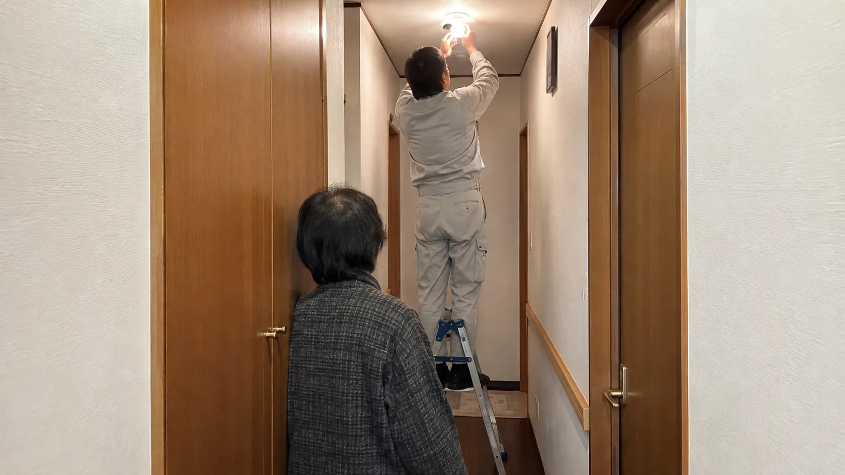 脚立に乗って高い場所の作業を行う作業員
