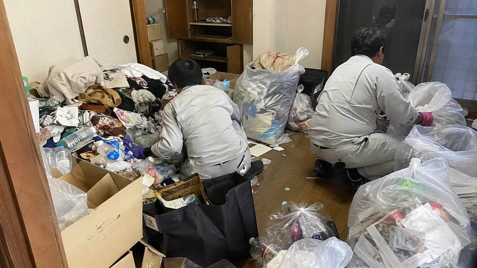室内にたまった不用品を分別して袋にまとめる作業員2名