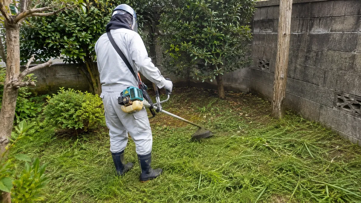 刈払機でお庭の草を刈る作業員