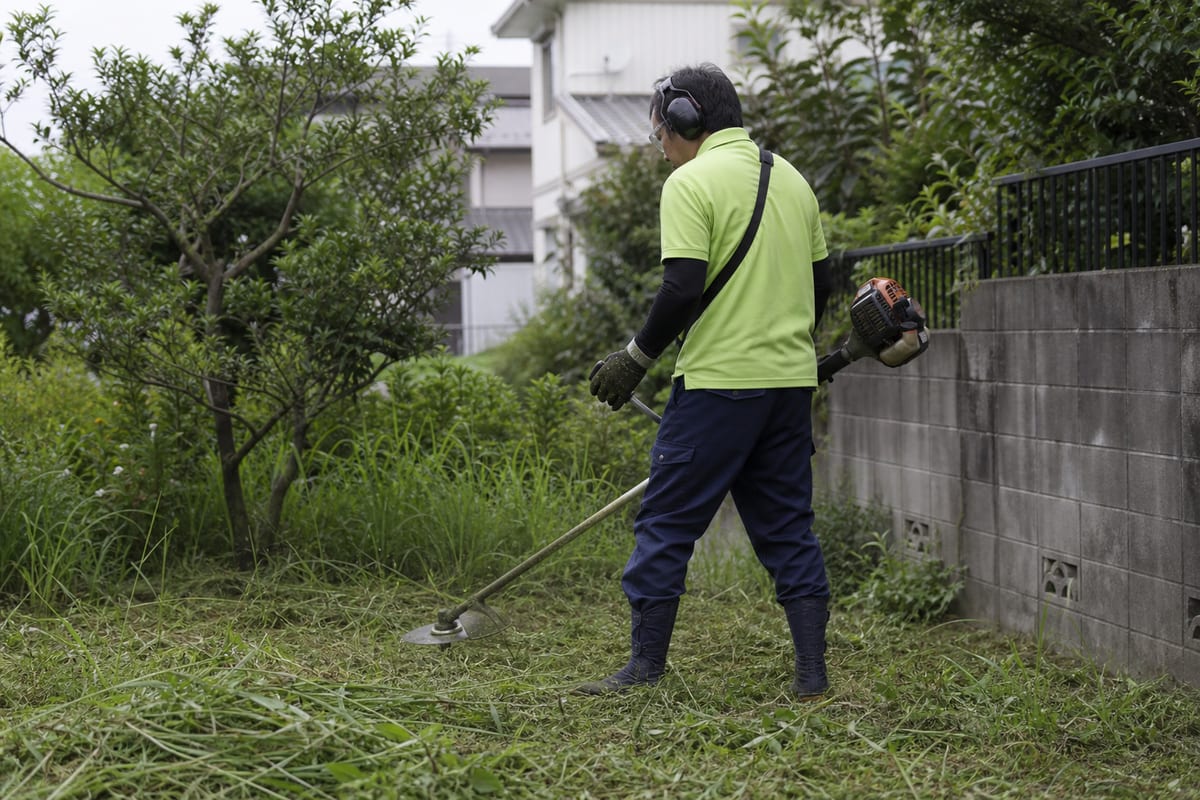 安全装備を着用して庭の草を刈るスタッフ